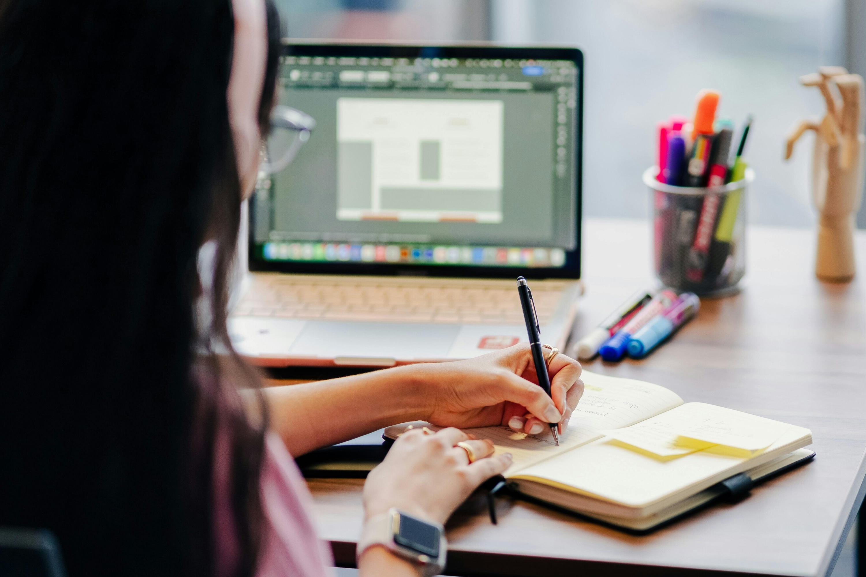 A photo of a woman taking notes in front of a computer screen